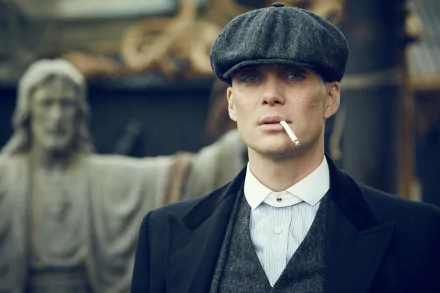 HD wallpaper of a stern-looking man in early 20th-century attire with a flat cap and a cigarette, evoking the mood of the TV show Peaky Blinders.