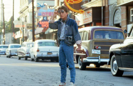 HD desktop wallpaper showing a scene from the movie Back To The Future with a person dressed in 1980s attire walking on a vintage street setting.