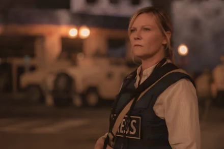 HD wallpaper featuring Kirsten Dunst in character, with a serious expression, wearing a vest with PRESS across the front against a dusk-lit backdrop with military vehicles, suggesting a scene from the movie Civil War (2024).