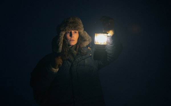 HD wallpaper featuring a mysterious scene from the TV show Constellation (2024) with a character in winter attire holding a lantern in the dark.