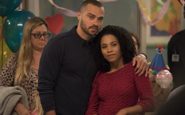A scene from Grey's Anatomy featuring two characters together in a warm moment, with a festive background and colorful decorations, set as an HD desktop wallpaper.