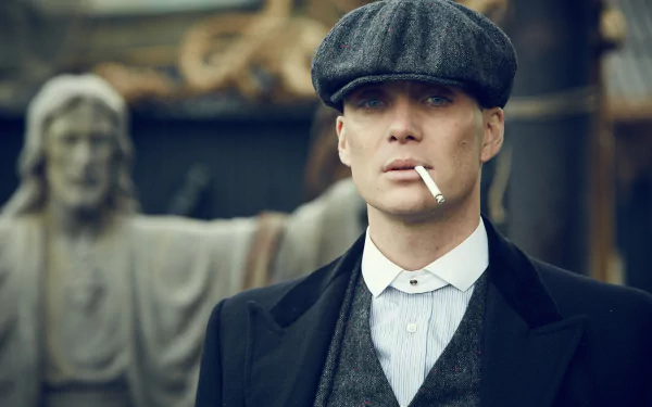 HD wallpaper of a stern-looking man in early 20th-century attire with a flat cap and a cigarette, evoking the mood of the TV show Peaky Blinders.