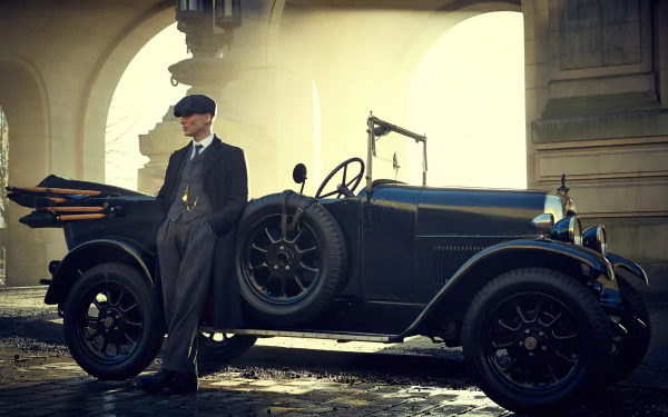 HD wallpaper featuring a character resembling Thomas Shelby from the TV show Peaky Blinders, played by an actor similar to Cillian Murphy, leaning on a classic car under an archway.