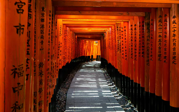 A scenic view of the iconic Fushimi Inari-taisha in Kyoto, Japan, showcasing a vibrant tunnel of red torii gates guiding a tranquil pathway.