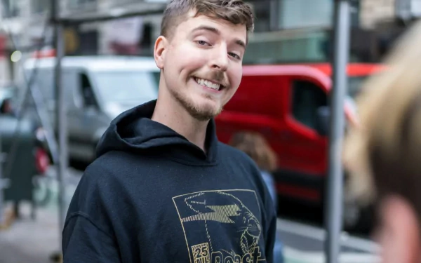 Smiling young man in black hoodie on busy street for HD desktop wallpaper background tagged with Mr. Beast.