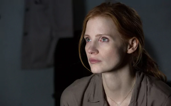 HD wallpaper featuring an introspective moment from the movie Interstellar with a female character showing a thoughtful expression in a dimly lit room.