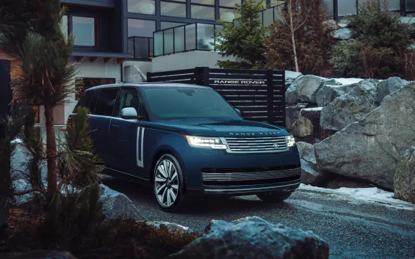 HD desktop wallpaper of a Range Rover SV car parked outside, amidst rocks and foliage.