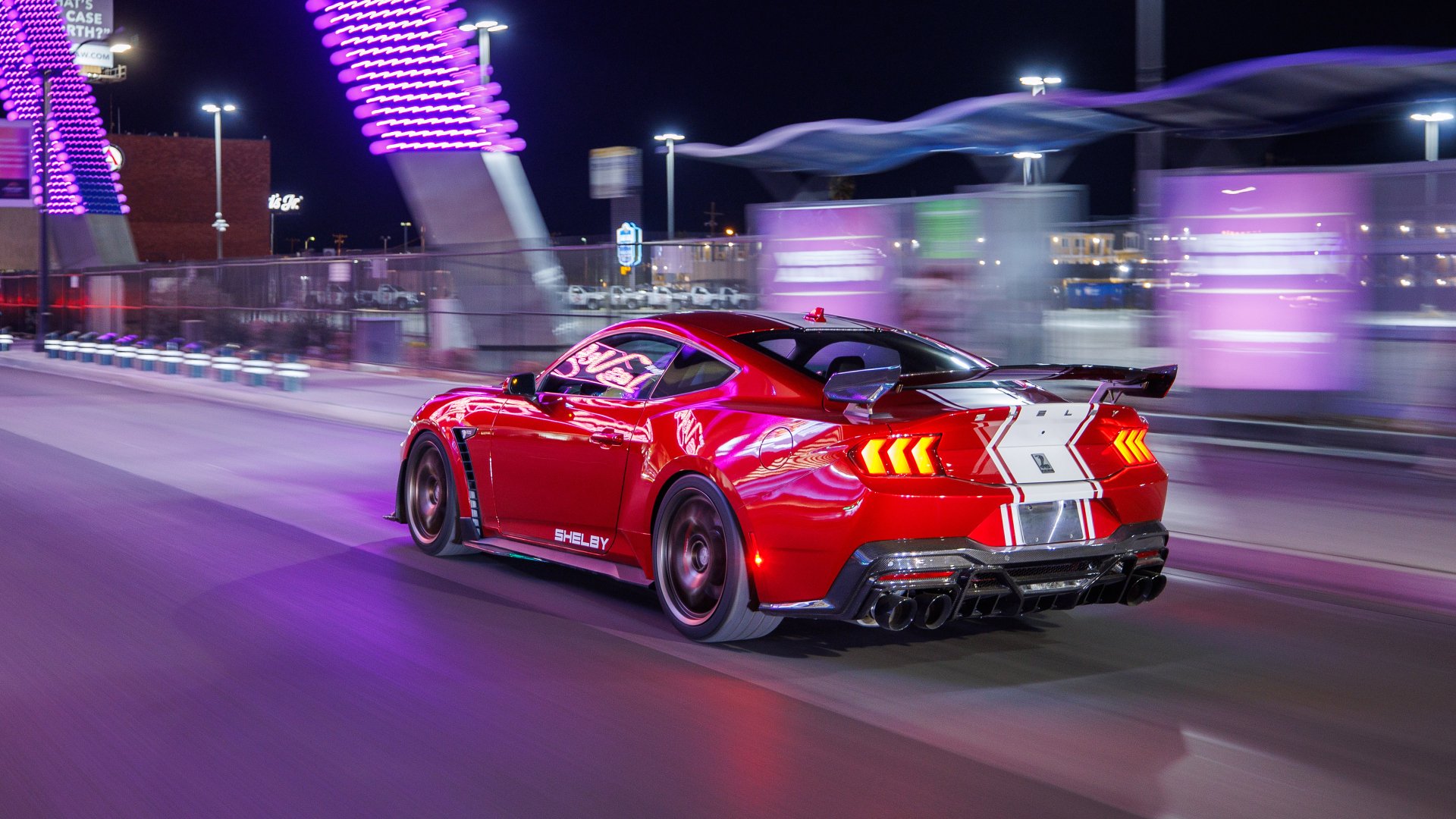 Red Shelby Super Snake muscle car in motion on a city street at night, showcased as a high-definition desktop wallpaper.
