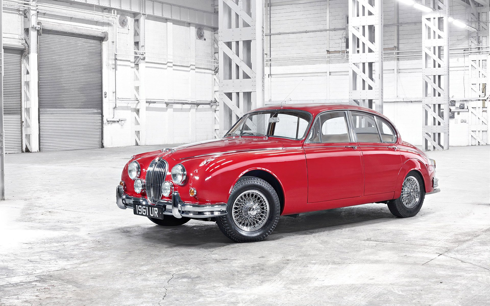 HD desktop wallpaper featuring a red Jaguar Mark 2 car in a spacious, industrial setting.