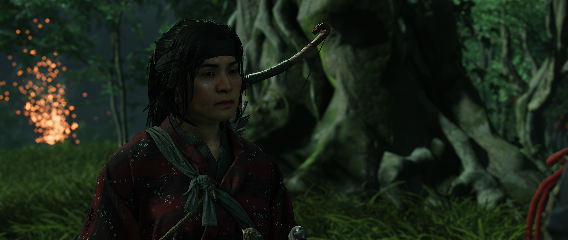 HD PC desktop wallpaper featuring a character from Ghost of Tsushima in a dimly lit forest, highlighting detailed textures and atmospheric shadows.
