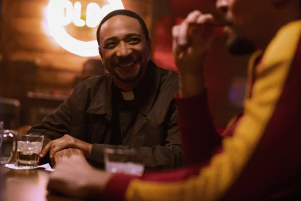 A still from the TV show 'The Big Door Prize' featuring two characters enjoying a conversation in a bar with a warm, cozy atmosphere, suitable as an HD desktop wallpaper or background.
