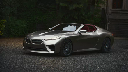 HD desktop wallpaper featuring a sleek, metallic BMW Skytop parked on a gravel surface with a lush green background.