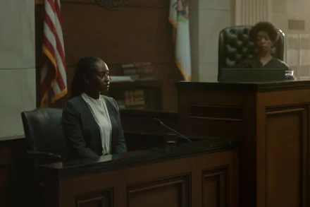 A courtroom scene from the TV show Presumed Innocent (2024), featuring a witness on the stand and a judge overseeing the proceedings, set against a backdrop of legal decor.