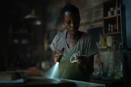 HD desktop wallpaper from A Quiet Place: Day One featuring Lupita Nyong'o in a dimly lit scene, holding a flashlight and string, highlighting the suspenseful atmosphere of the movie.