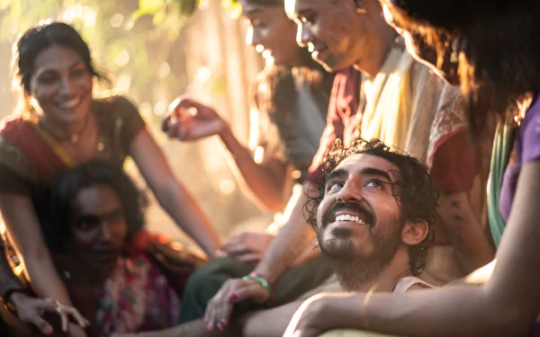 HD desktop wallpaper from Monkey Man (2024) featuring a joyous scene with a group of people smiling and interacting in a sunlit setting.