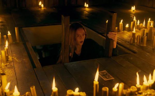 HD desktop wallpaper from Tarot (2024) featuring a scene with a woman surrounded by candles in a mysterious, dimly lit wooden setting.