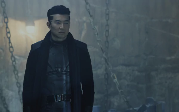 HD desktop wallpaper and background from the 2024 movie Atlas, featuring a man in a dark outfit standing in a dimly lit, industrial setting with chains hanging in the background.