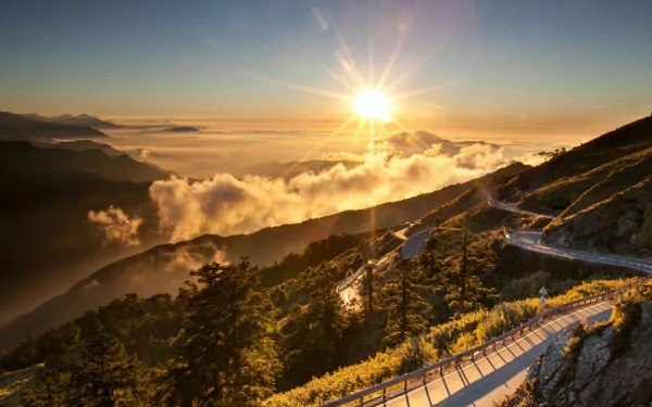 The HD desktop wallpaper depicts a stunning Taiwan landscape with a winding road leading through lush green mountains, bathed in the golden sunbeam of dawn.