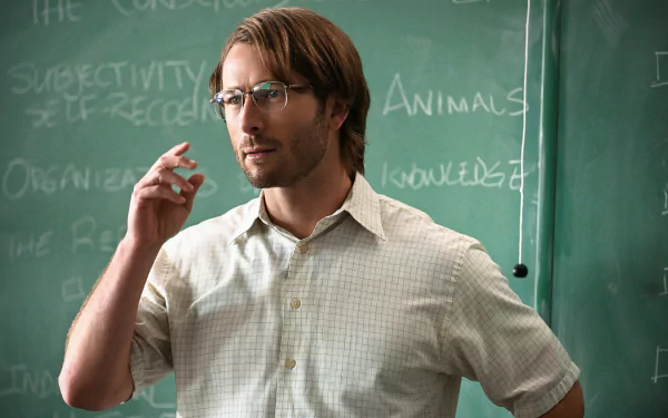 HD desktop wallpaper featuring Glen Powell in the 2023 movie Hit Man, standing in front of a chalkboard, wearing glasses and a checkered shirt.