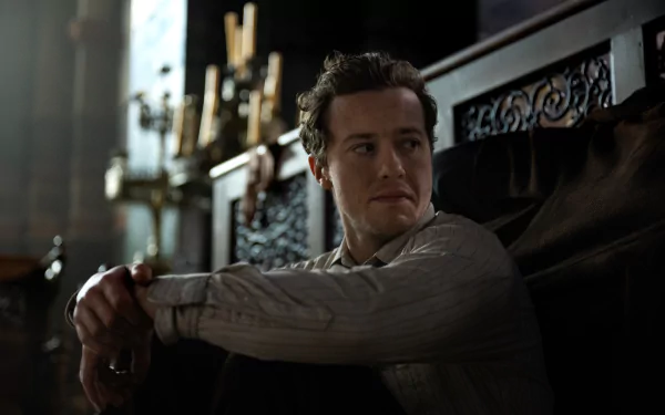 HD desktop wallpaper featuring a scene from the movie A Quiet Place: Day One with Joseph Quinn, showcasing his character in a contemplative pose against a dimly lit, intricate background.