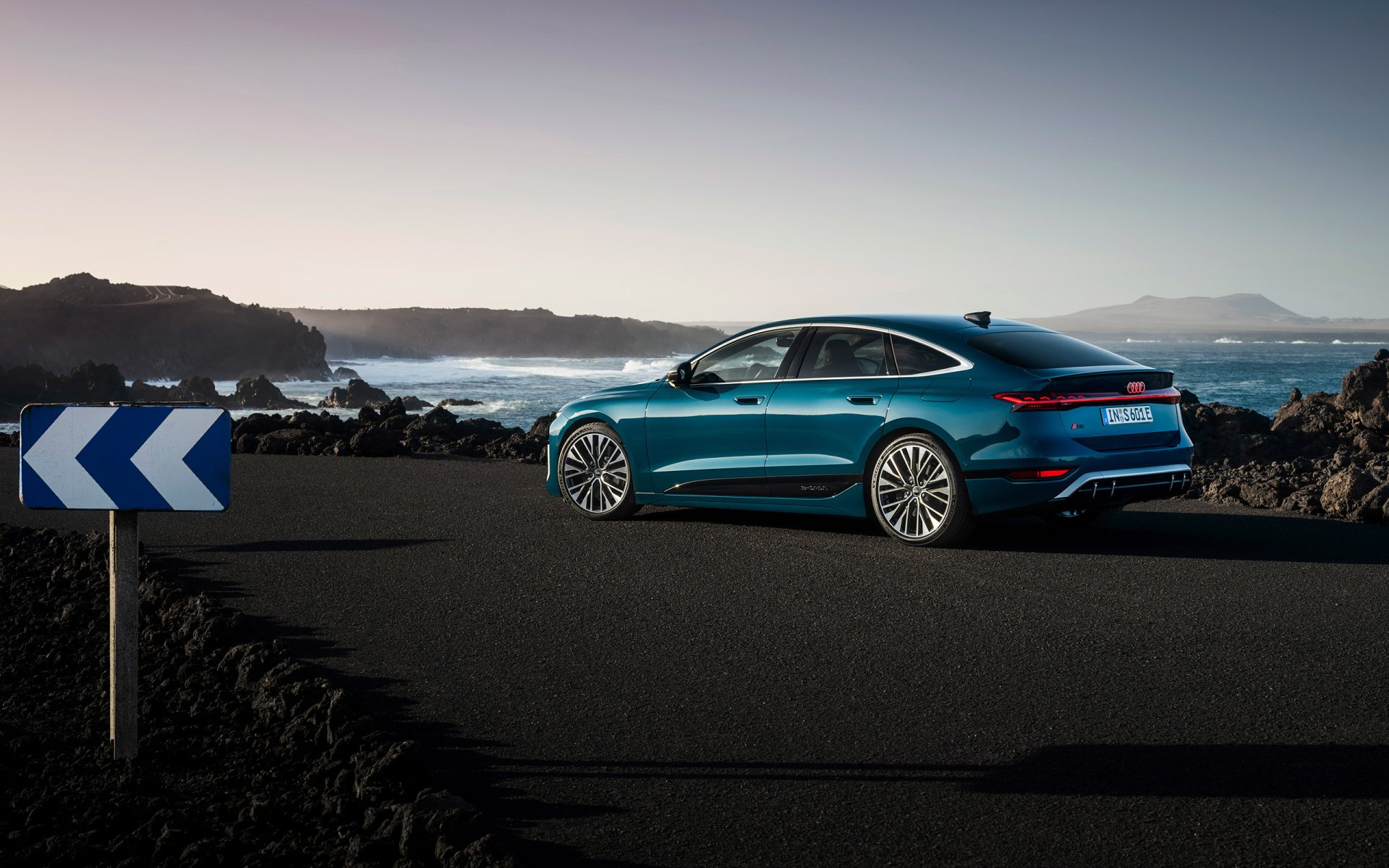 A stunning Audi S6 E-Tron parked on a coastal road with a clear view of the ocean, showcasing its sleek design against a picturesque backdrop. HD desktop wallpaper.