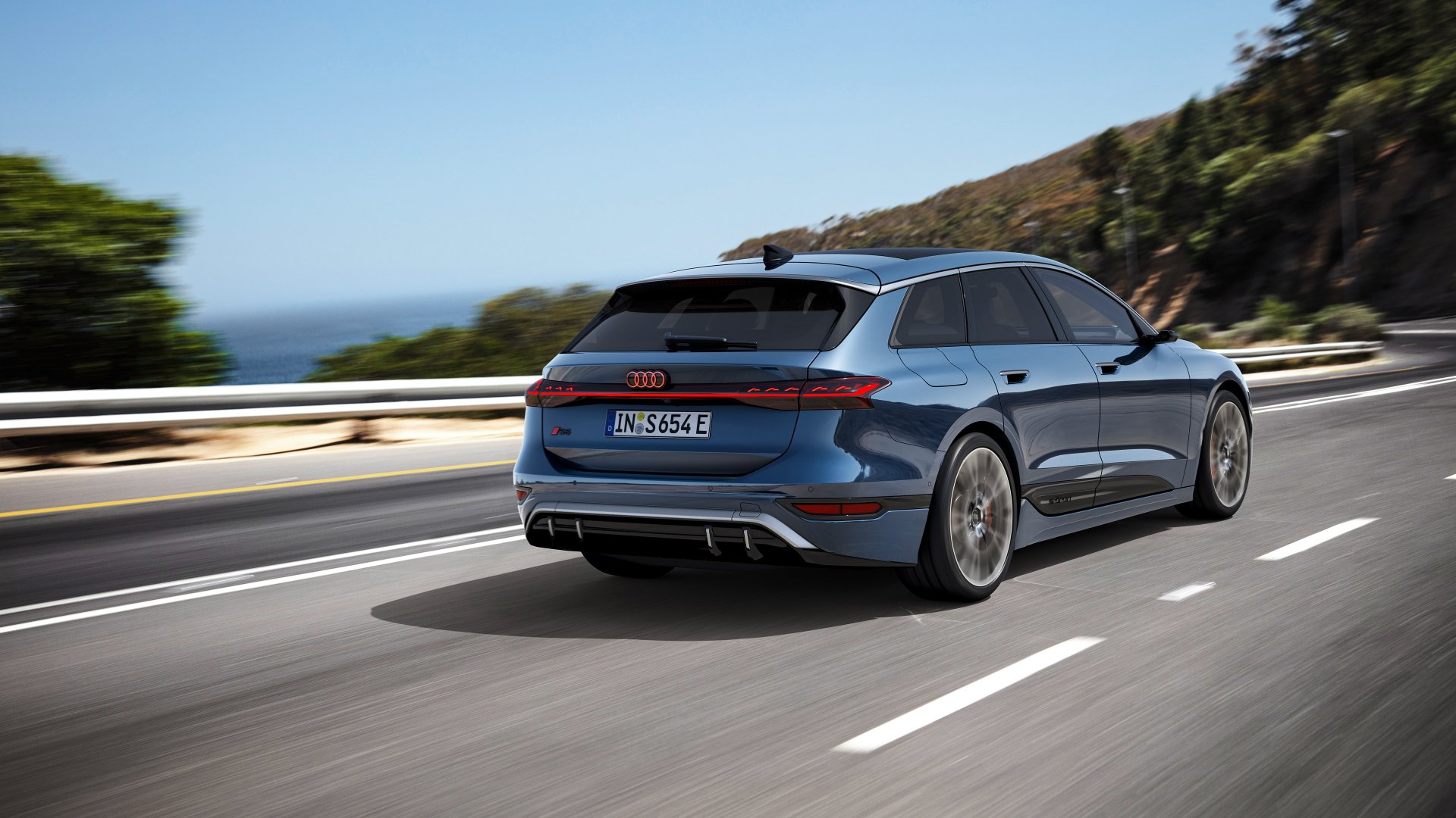 A striking Audi S6 E-Tron drives along a scenic road, showcasing its sleek design against a backdrop of hills and ocean, captured in stunning 4K Ultra HD quality.