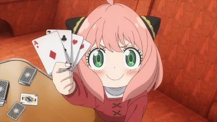 Anya Forger from Spy x Family Code: White holding playing cards with a confident smile, featured in a vibrant HD anime desktop wallpaper.