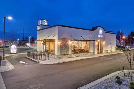 4K Ultra HD image of a man-made Taco Bell fast food restaurant at dusk, featuring illuminated signage and a quiet parking area.