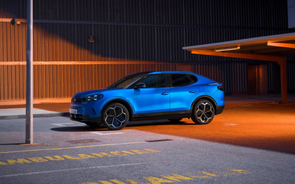 A vibrant blue Ford Capri parked in an urban setting, illuminated by warm lighting. This HD wallpaper captures the sleek design and modern appeal of the iconic car.