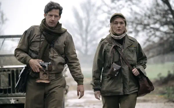 A scene from the movie Lee (2023) featuring Kate Winslet and Andy Samberg walking together in military attire, captured in a 4K Ultra HD wallpaper.