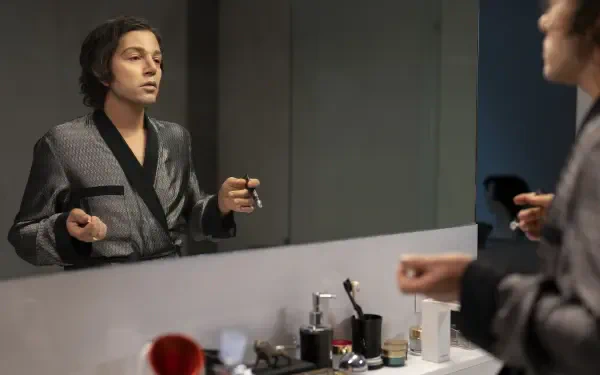 A scene from the TV show La Máquina (2024), featuring a character in a robe applying makeup while gazing into a mirror, surrounded by various beauty products.