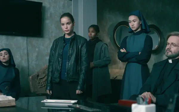 A scene from the TV show Warrior Nun, featuring Alba Baptista and fellow cast members in a tense gathering, set against a modern, minimalistic background.