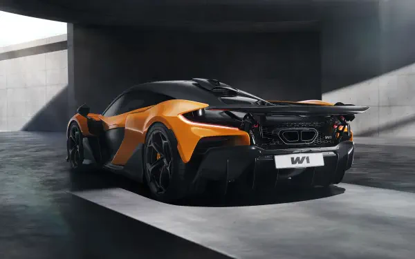 A stunning McLaren W1 in vibrant orange and sleek black, showcased in an architectural setting. This 8K Ultra HD image serves as an impressive desktop wallpaper.