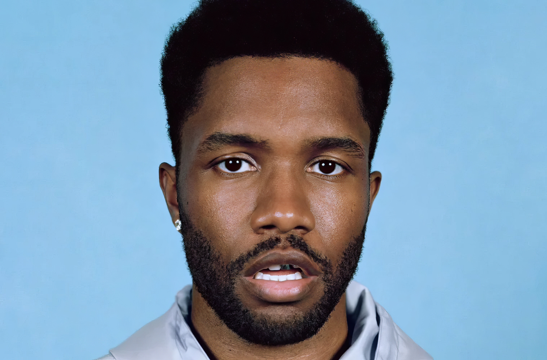 Close-up of Frank Ocean, featuring his expressive gaze against a light blue background. This HD wallpaper captures the essence of the artist and complements any music-themed desktop.