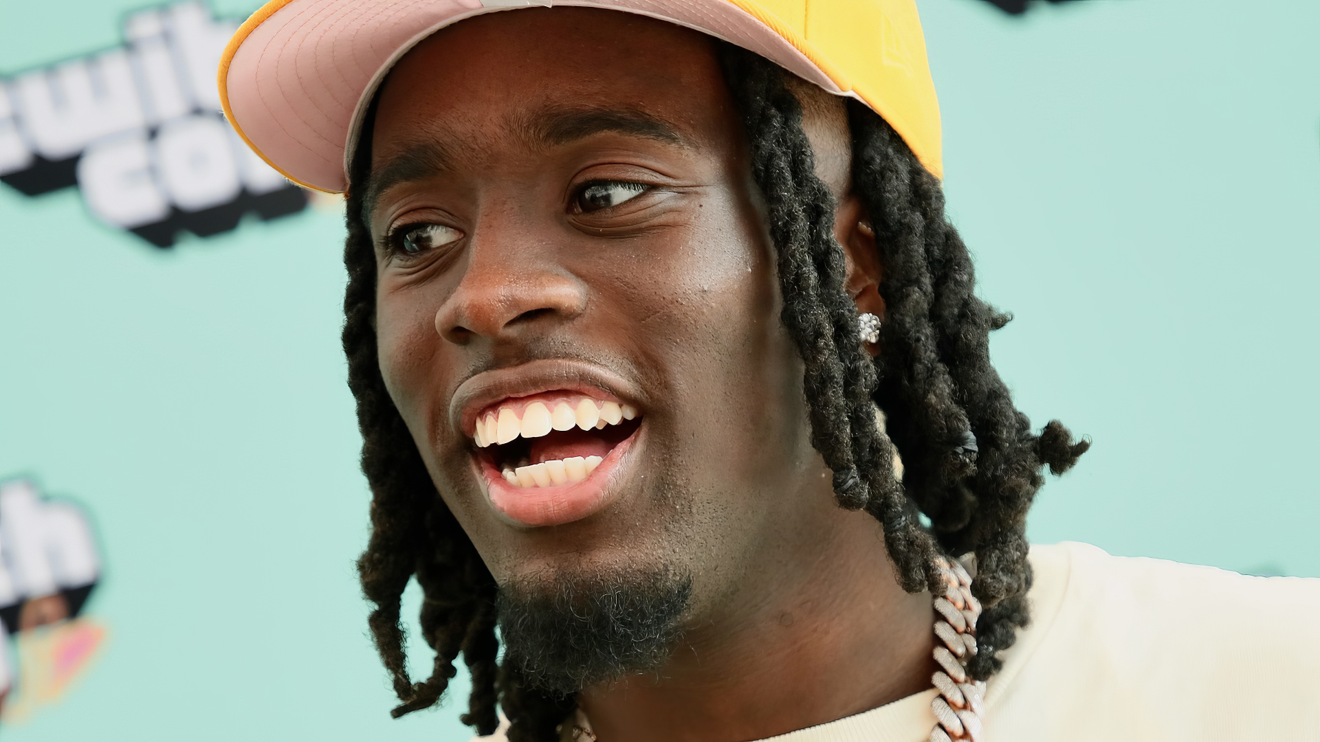 A vibrant HD desktop wallpaper featuring Kai Cenat, the popular streamer and celebrity, smiling and showcasing his distinctive style against a playful background.