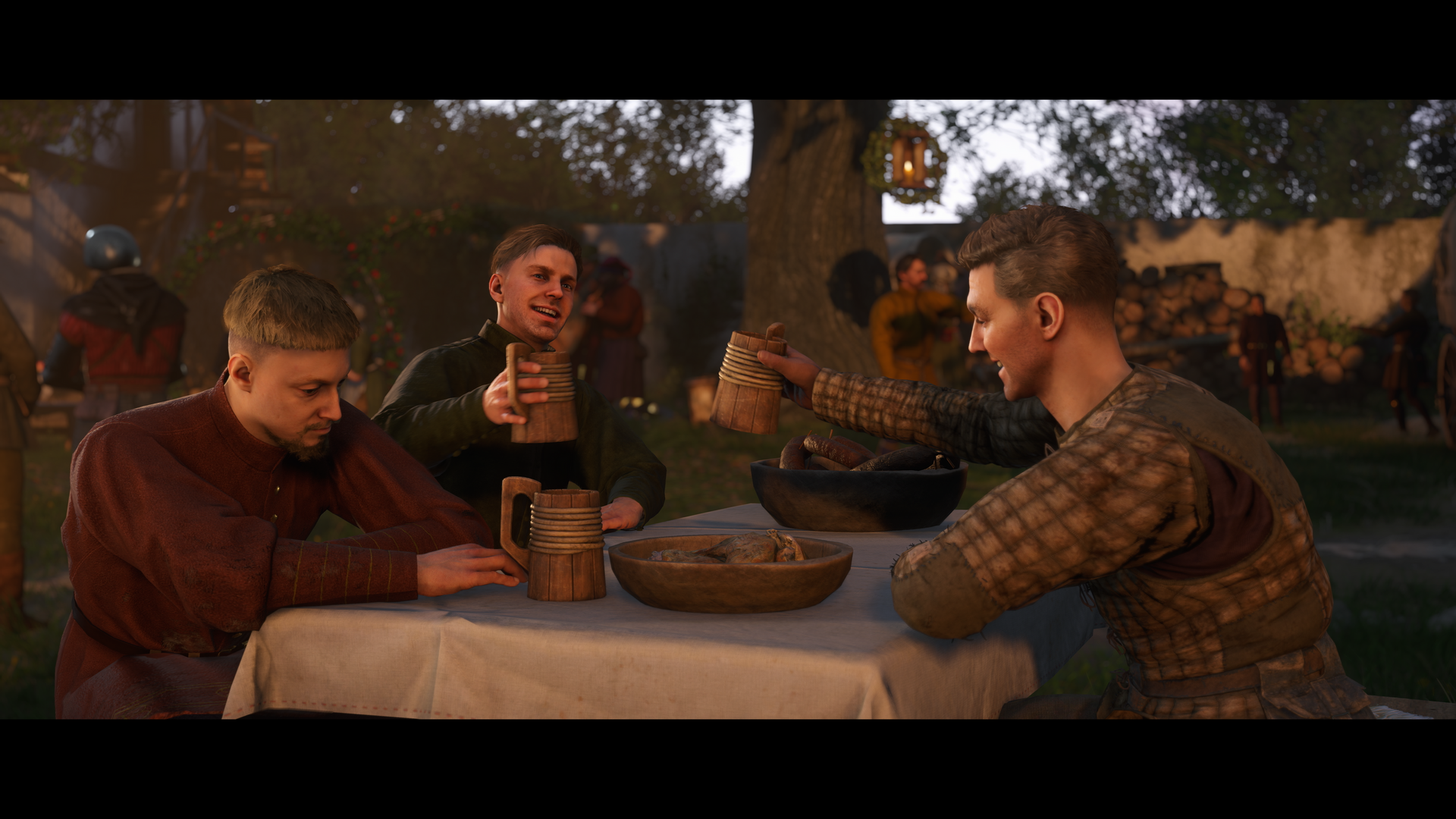 A HD wallpaper from Kingdom Come: Deliverance II, depicting three characters at a table celebrating with drinks, set against a lively outdoor scene.