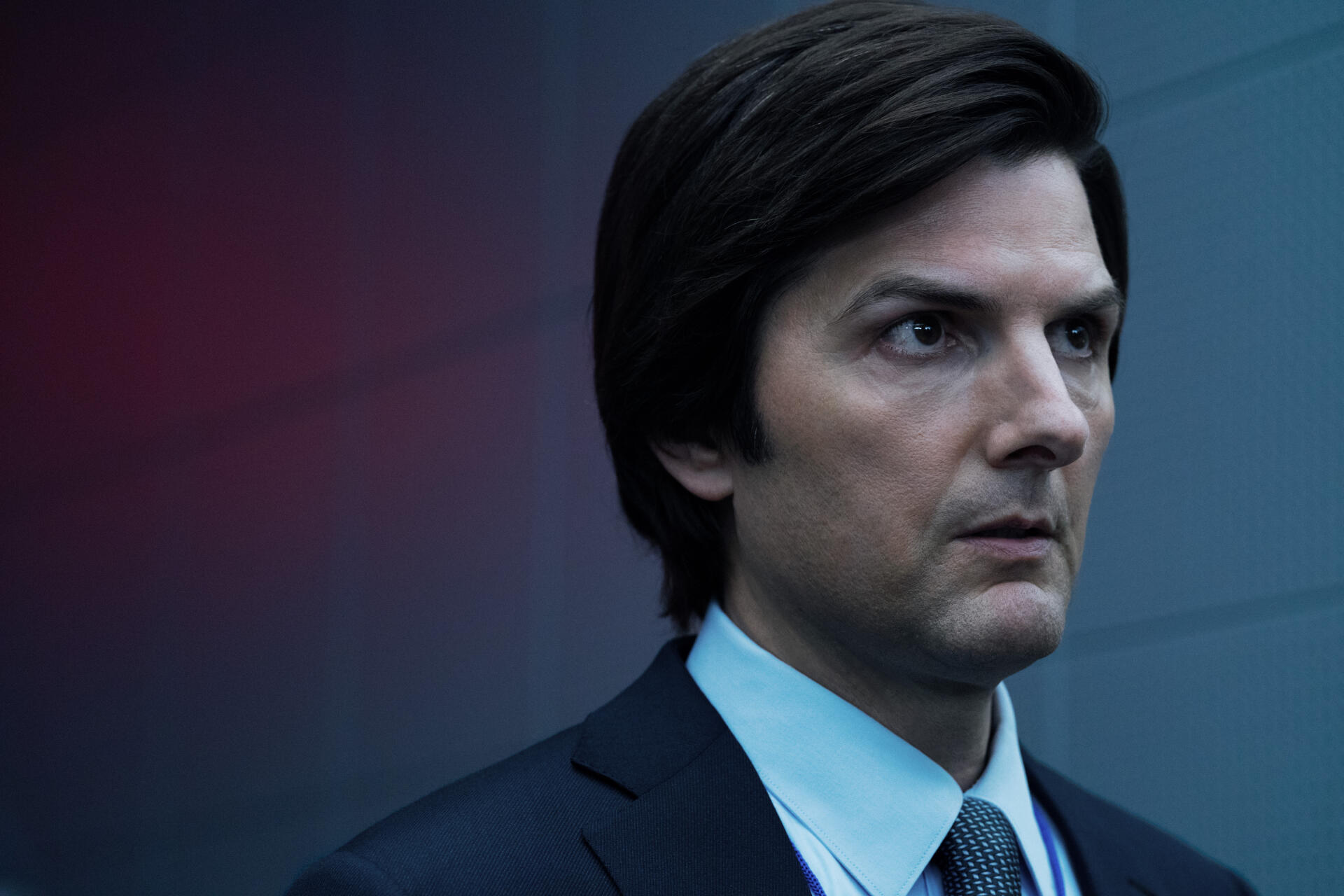 A close-up of Adam Scott in a dramatic scene from the TV show *Severance*, featuring a sharp, intense expression in a sleek, corporate setting. 4K Ultra HD desktop wallpaper.