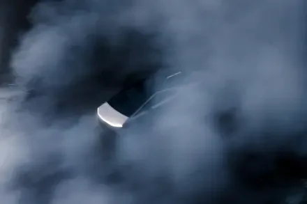 A Tesla Cybertruck partially emerges from a dense fog, showcasing its distinctive design and futuristic appeal. This high-definition image serves as a striking desktop wallpaper.