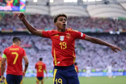 Lamine Yamal celebrates a goal during a match for the Spain National Football Team, showcasing vibrant team spirit against a cheering crowd. HD wallpaper for soccer fans.