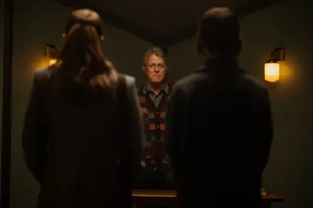 Hugh Grant stars in Heretic (2024), captured in this intense scene featuring two silhouettes confronting him, set in a dimly lit room. 4K Ultra HD desktop wallpaper.