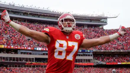 Travis Kelce celebrates in front of a vibrant crowd during a Kansas City Chiefs NFL game, showcasing the energy and passion of football. High-definition desktop wallpaper.