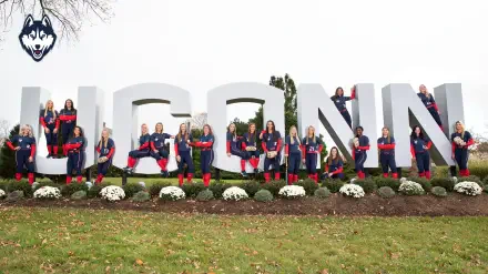 UConn Athletics team poses in front of large UConn signage, showcasing school spirit in a vibrant display. This HD wallpaper captures the pride and camaraderie of the athletes.