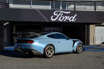 4K Ultra HD wallpaper showcasing a light blue Ford Mustang GTD parked outside a Ford dealership under a bold Ford logo sign.