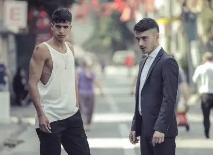 Two young men stand on a street in an urban setting, showcasing a contrasting style. This image is a 4K Ultra HD wallpaper inspired by the TV show The Pit.