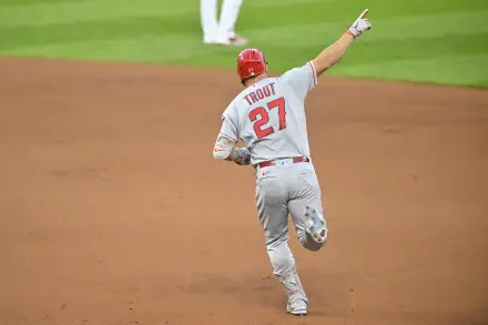 Mike Trout of the Los Angeles Angels celebrates during a game, wearing his Grey uniform with the number 27. A dynamic HD wallpaper capturing the spirit of MLB baseball.