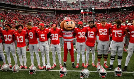 A vibrant Ohio State Buckeyes football scene featuring players in red jerseys and a mascot, set against a lively stadium crowd, perfect as a desktop wallpaper.