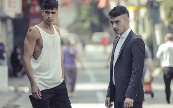 Two young men stand on a street in an urban setting, showcasing a contrasting style. This image is a 4K Ultra HD wallpaper inspired by the TV show The Pit.