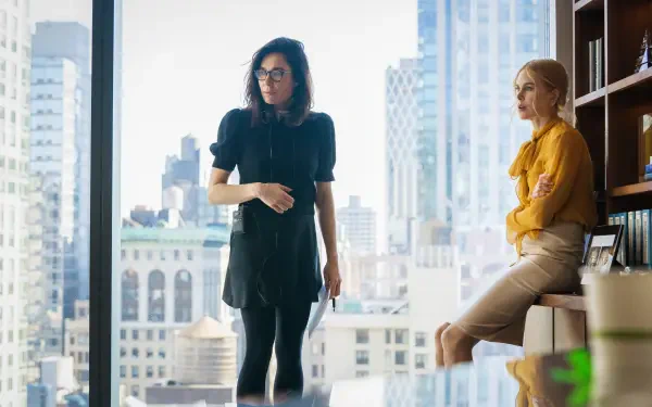 A scene from the movie Babygirl featuring Nicole Kidman, showcasing two women in a modern office with a city skyline in the background. 4K Ultra HD desktop wallpaper.