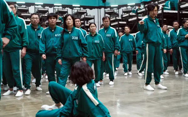 A scene from the TV show Squid Game, featuring contestants in green tracksuits standing in a dimly lit room, creating a tense atmosphere. 4K Ultra HD for a striking desktop background.