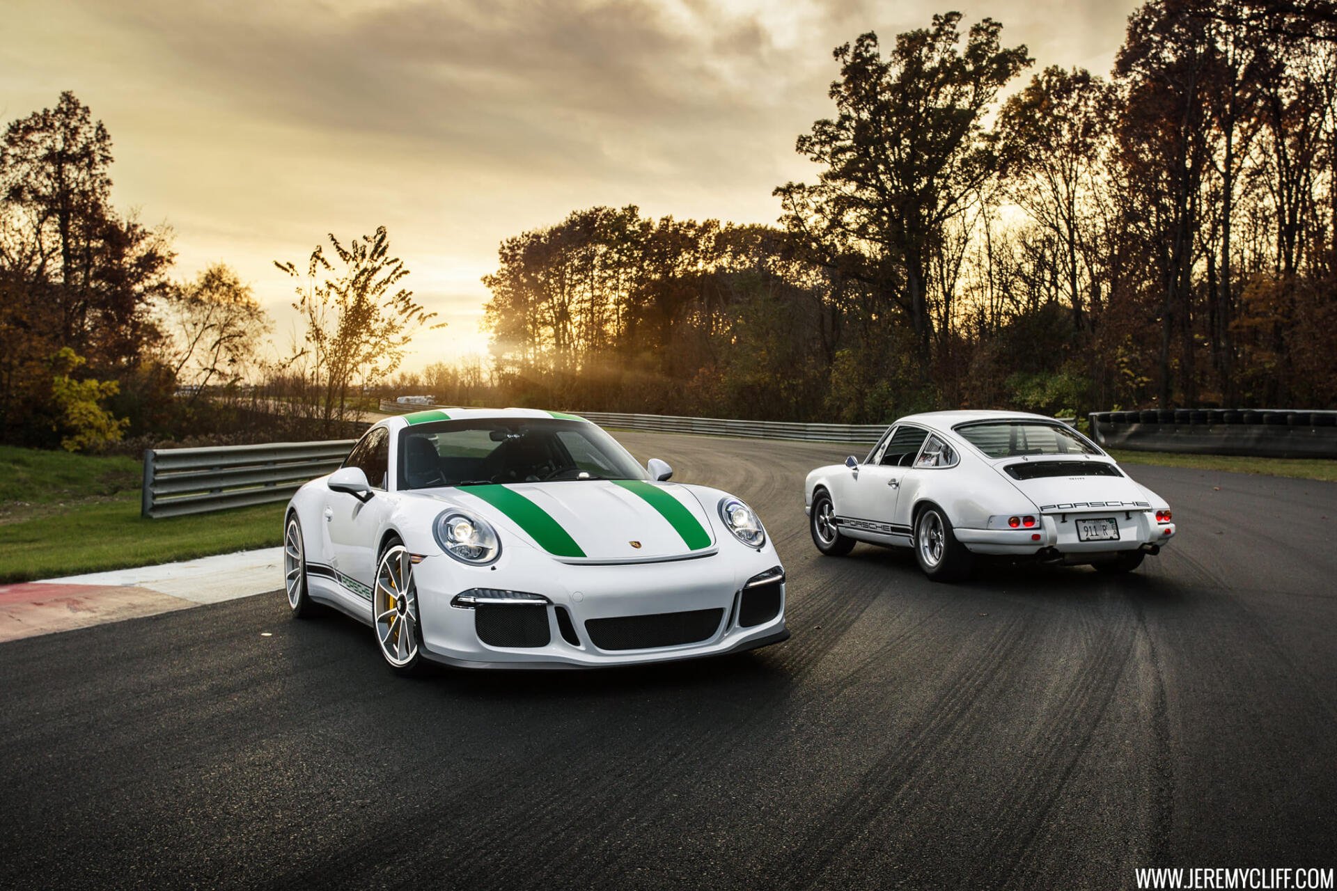 HD PC desktop wallpaper and background: two white Porsche cars on a racetrack at sunset — a modern 911 GT3 with green stripe beside a classic 911.